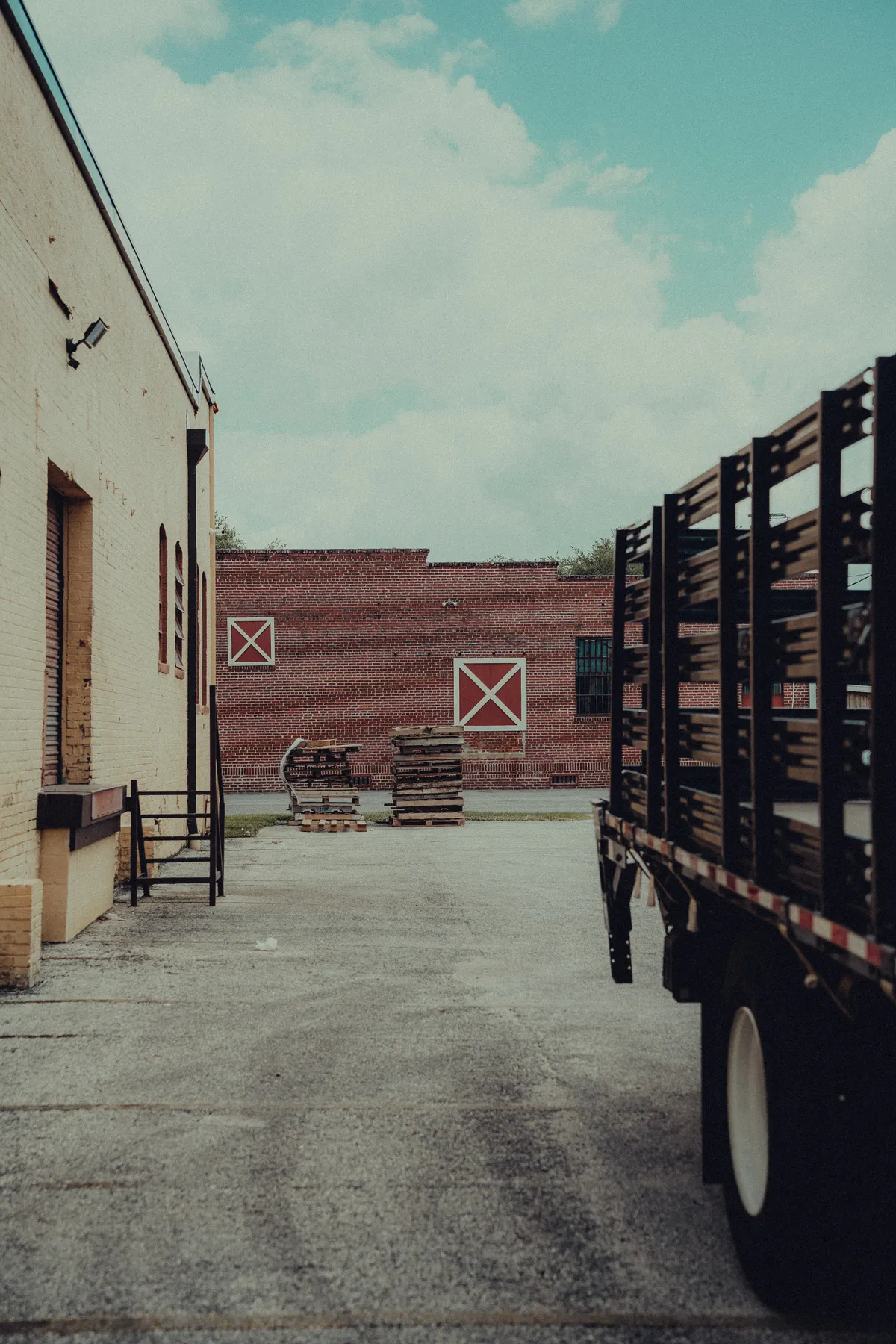 Flatbed truck alongside a brick warehouse loading yard